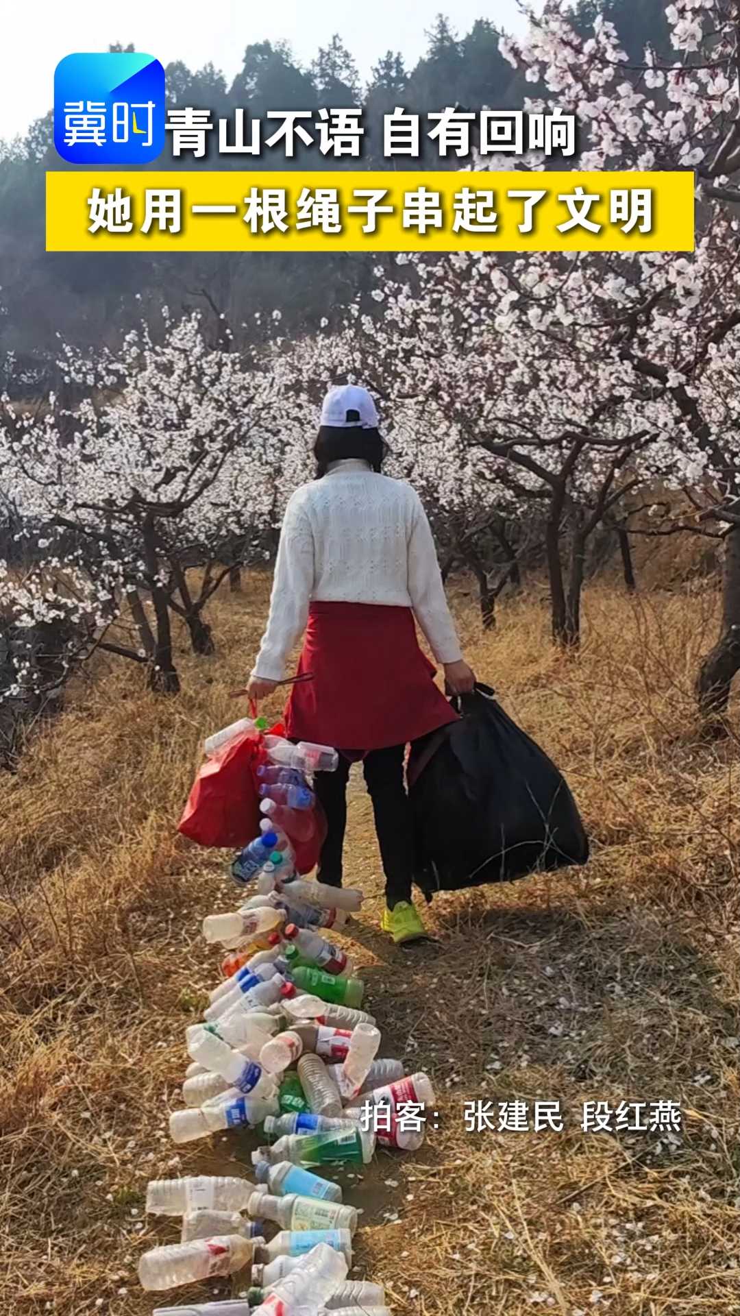 近日，一名登山爱好者，在攀登白塔山时，用绳子将游客丢弃的瓶子串在一起，双手拎着垃圾袋下山，她的身影与青山相映，成为一道动人风景。